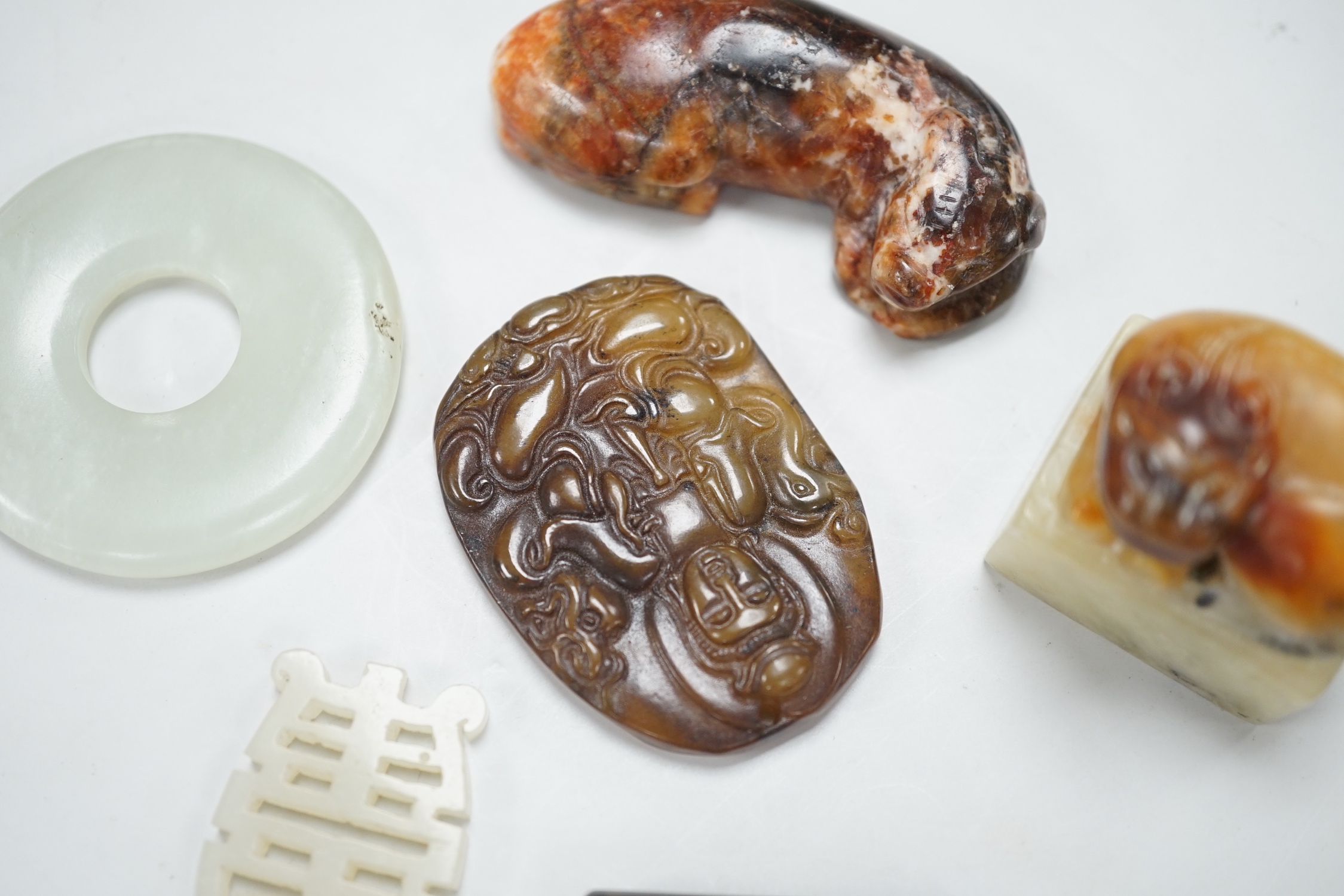 A Chinese pale celadon jade bi disc, a jade carving of the character ‘Shou’ , two hardstone carvings of creatures, an agate pendant of Guanyin in Tang dynasty style and a stained glass , bead in Tibetan style (6), disc 4